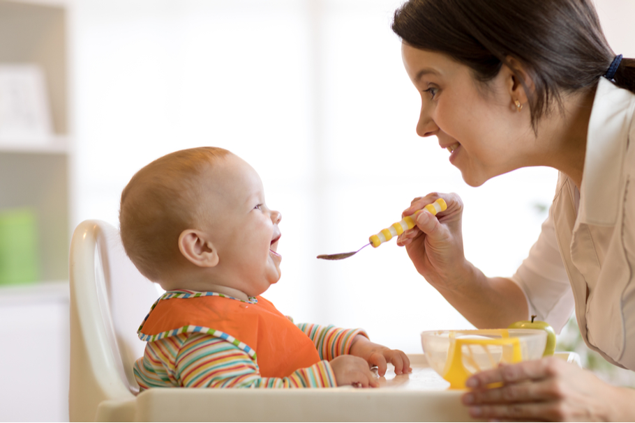 a parent feeds their baby a spoon of baby food