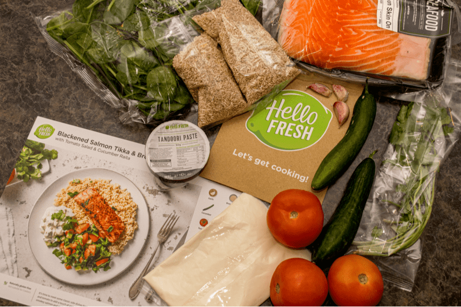 a hello fresh mealkit delivery filled with salmon, tomato, zucchini, fresh herbs and a recipe card